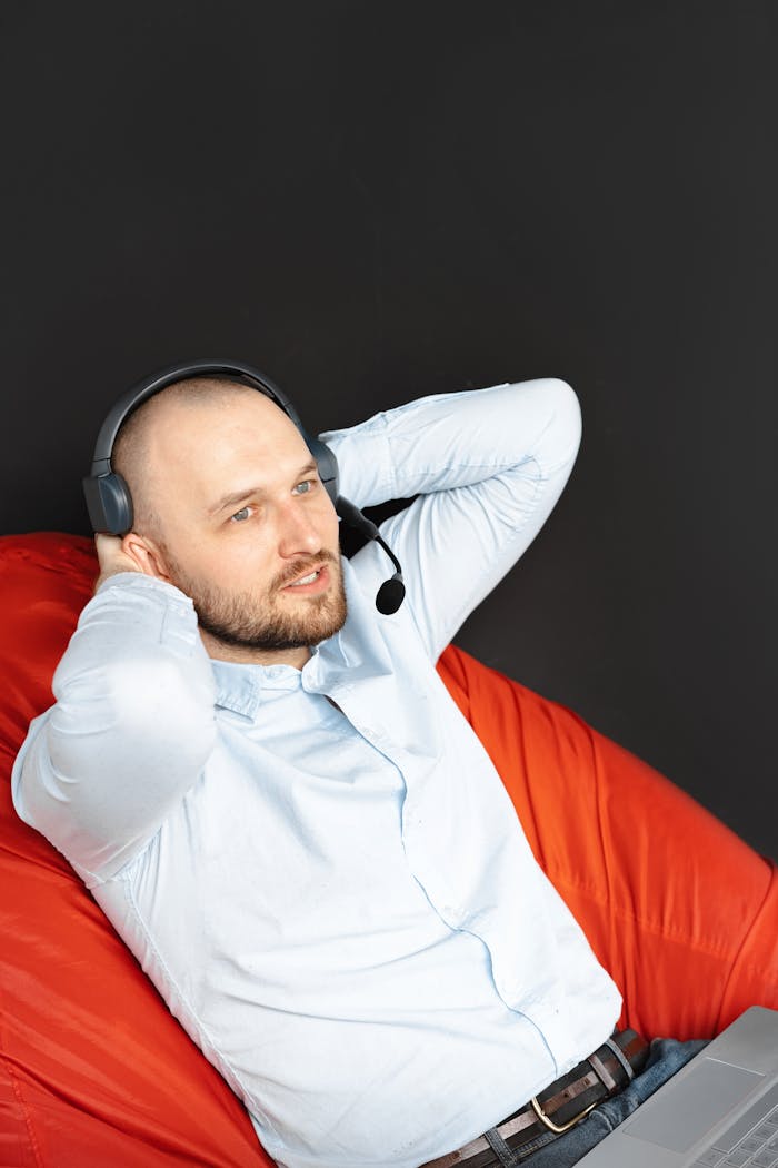 Caucasian man with headset relaxing in a modern office setting, providing remote assistance.